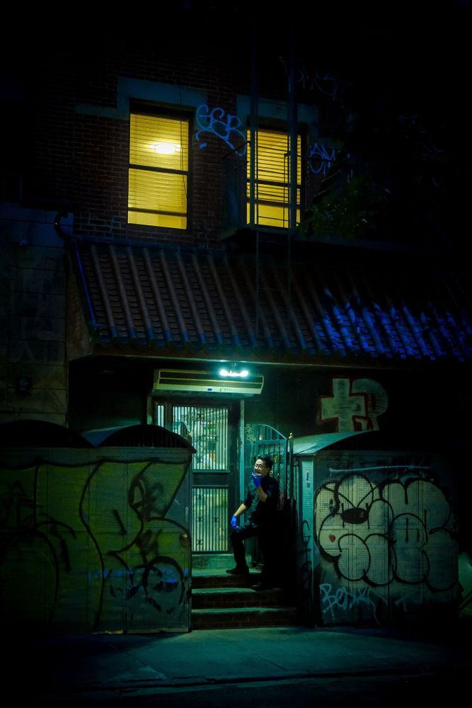 A person stands outside an illuminated doorway in the Lower East Side, Manhattan, New York.