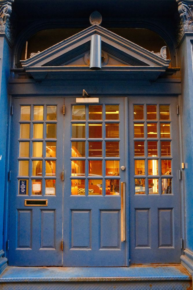 A blue double door with glass panels, warmly lit from within, in SoHo, Manhattan, New York.