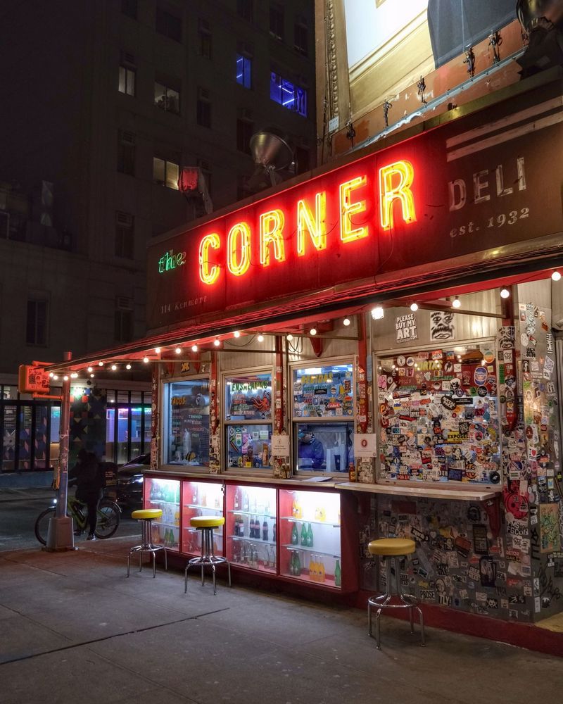 A vibrant urban scene featuring a Saint Laurent fashion billboard above The Corner Deli in Manhattan, New York.