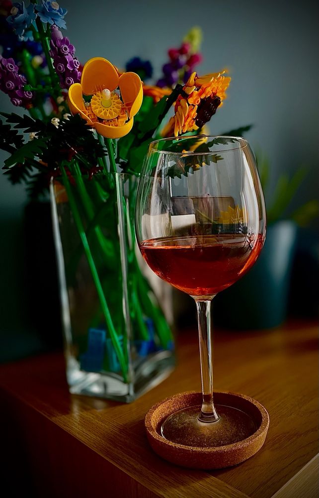 Glass of rose wine with Lego flowers in the background. 