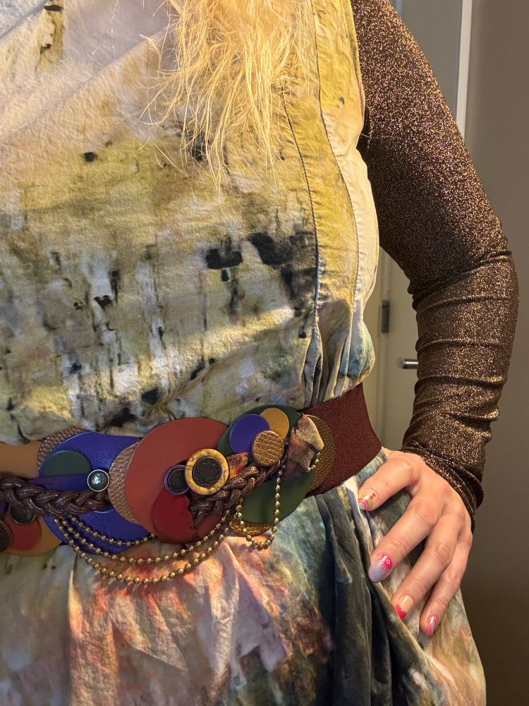 closeup of the belt, which has many colors and shapes and dangly bits (idk how to describe this I am so sorry)