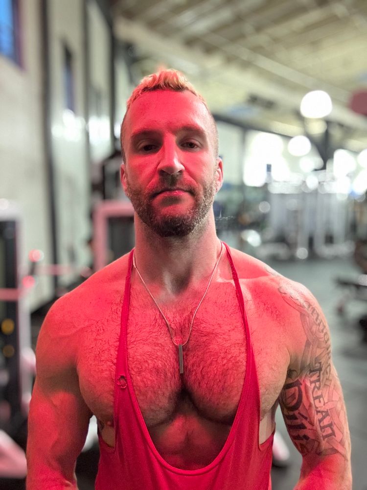 Gay guy at the gym wearing a red stringer tank with a hole on the right stringer thingy 