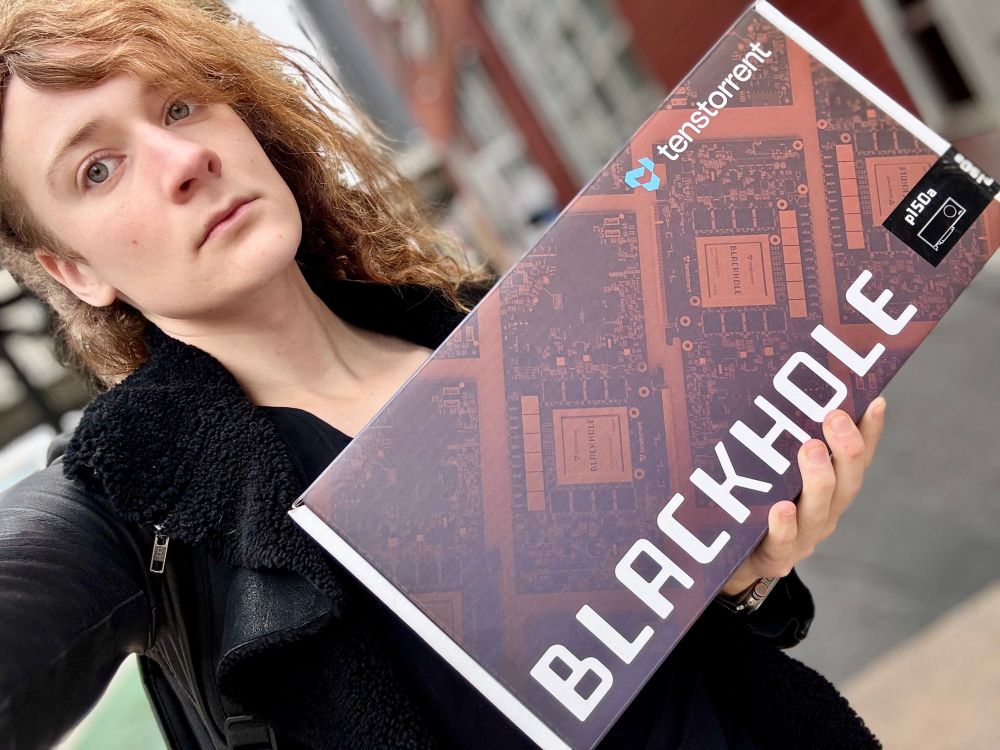 picture of me holding a box containing a Tenstorrent Blackhole accelerator card