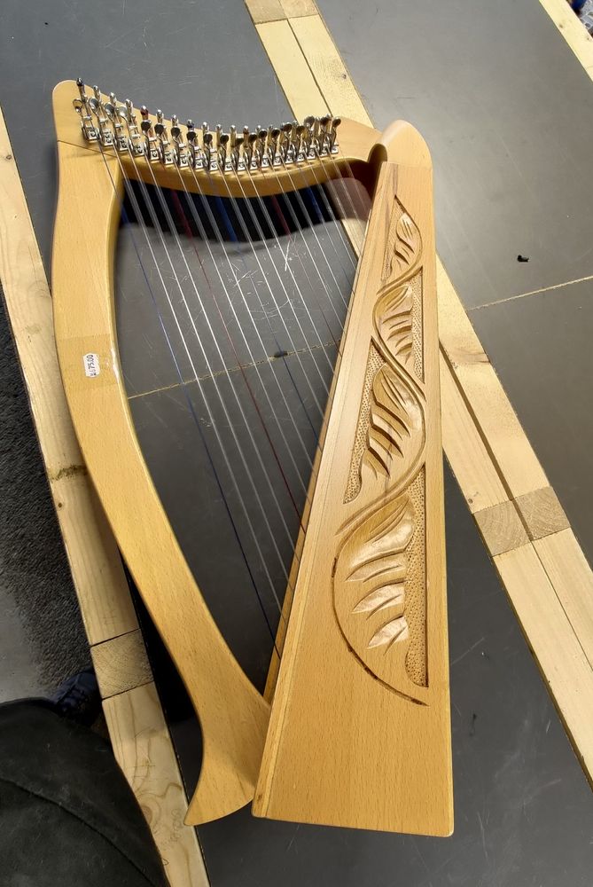 A nineteen string lever harp made of light brown wood. 