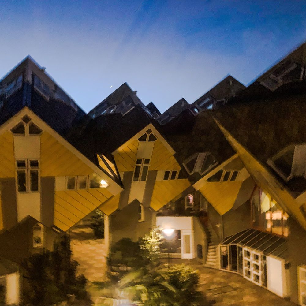 The Cube Houses are an architectural project where the square houses are set on one point of the cube on top of a brick structure that acts also as the entrance of the cube. The houses are stacked together tightly.
