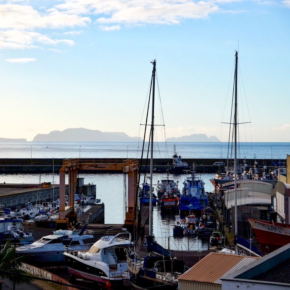 Picture of boats in the harbor of Caniçal, Madeira, Portugal. In the background you can see the islands of “Reserva Natural das llhas Desertas” sitting in the ocean
