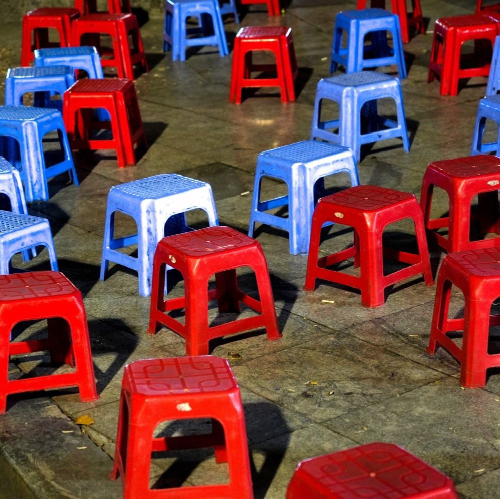 Many separately placed small red stools and blue stools made of plastic on the pavement in Hanoi Vietnam 