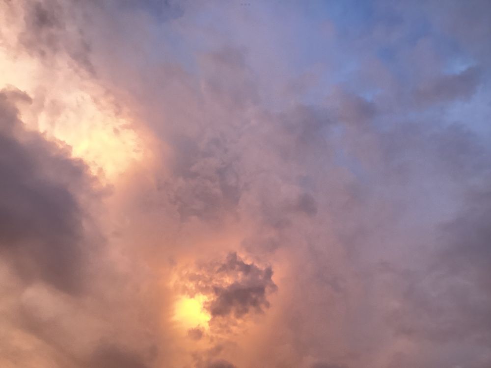 Sunset after a rainy afternoon/early evening with clouds in yellow/gold and light gray colors.