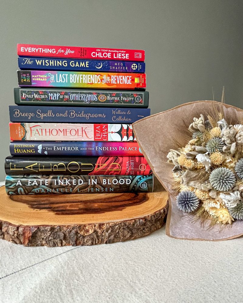 Book stand on a wooden tray with a bouquet of dried flowers next to it. 