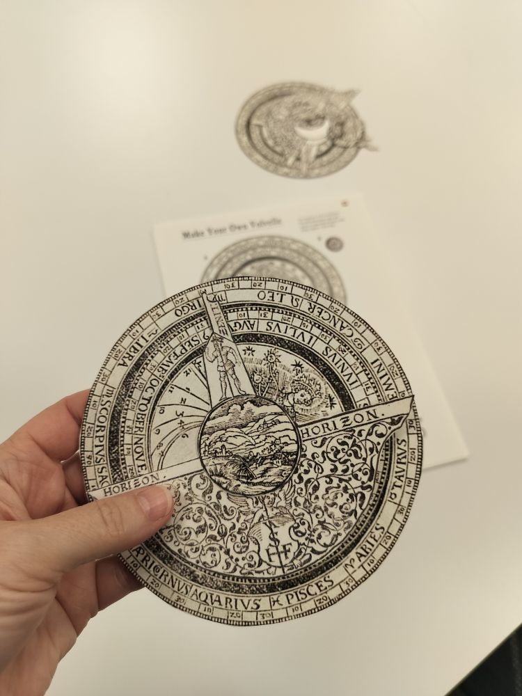 Photo of a hand holding a paper volvelle