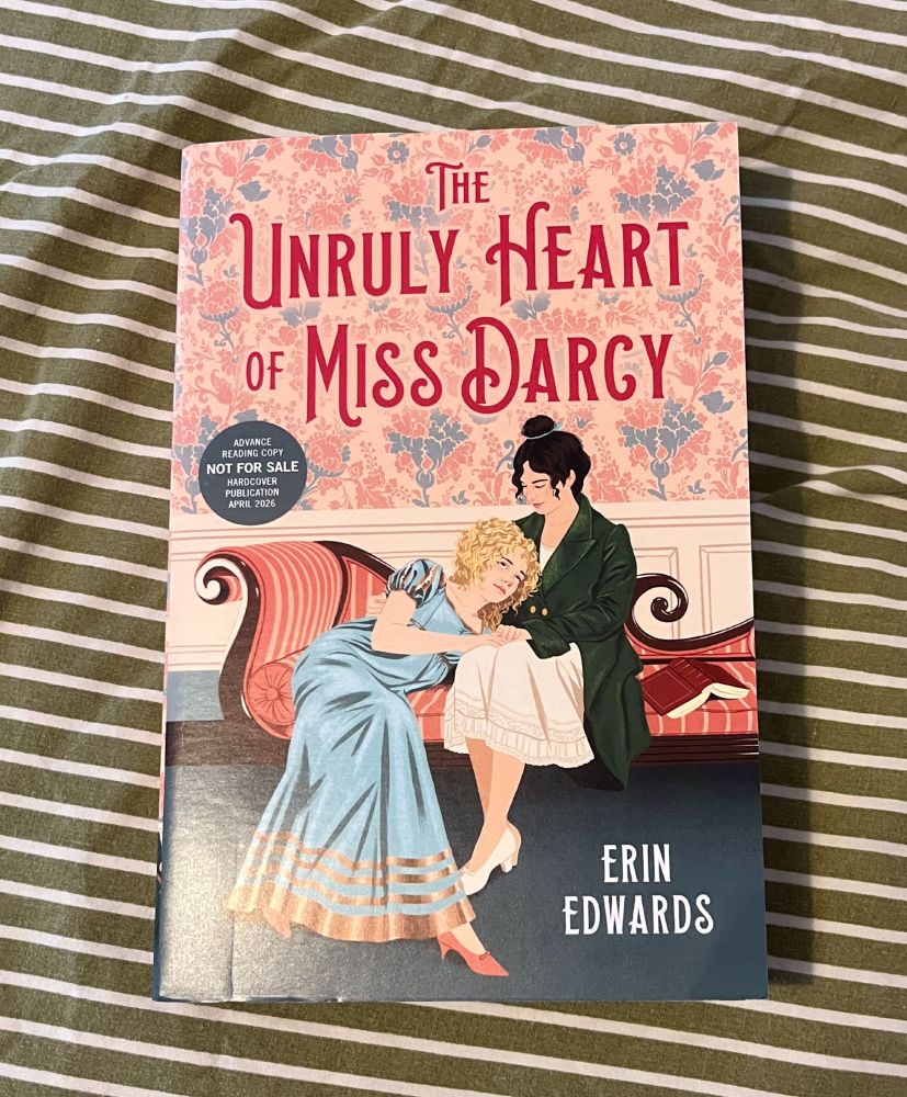 a proof paperback of The Unruly Heart of Miss Darcy by Erin Edwards, with an illustration showing two girls sitting on a chaise longue, one lying in the others lap.