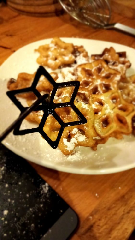 Photo de beignets au fer en forme d'étoiles. Au premier plan le moule en fer.