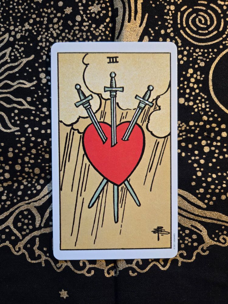 The three of swords to row card from the Rider Waite Smith deck on a tree of life altercloth. 