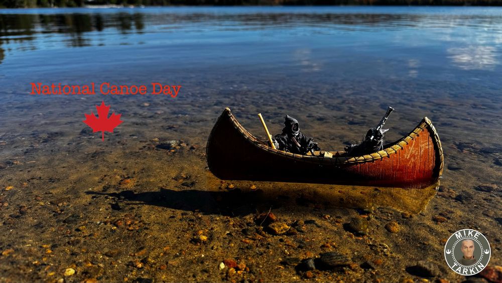 2 Jawa action figures sitting in a toy sized canoe on a Canadian lake. 
