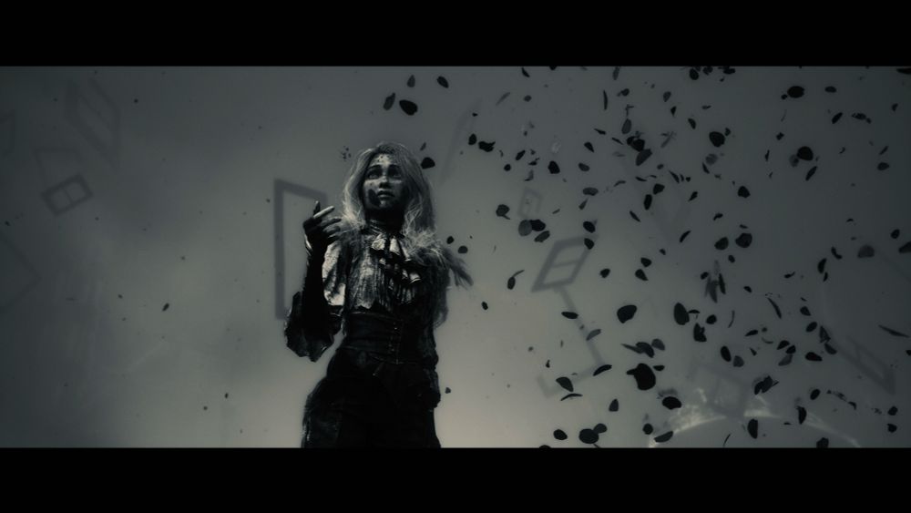 A silver tone screenshot of Clair Obscur. A young woman (Maelle) stands against the sky as flower petals blow past her.