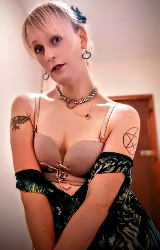 A woman wearing a sundress, pulled down past her chest to reveal her bra.