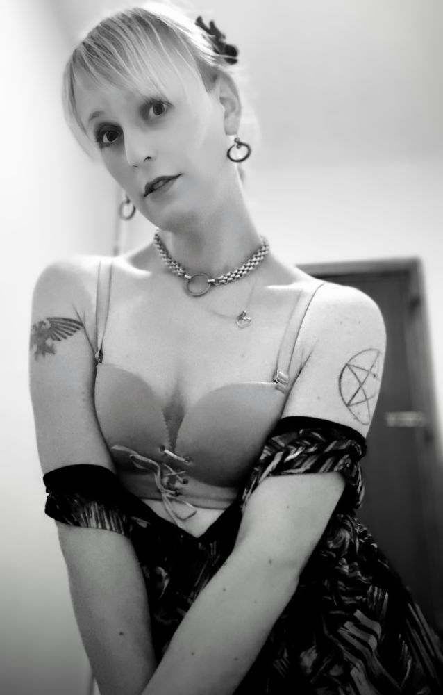 A woman wearing a sundress, pulled down past her chest to reveal her bra.