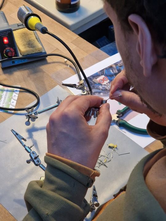 A man holding electronic components soldered together into some kind of hexapedal animal
