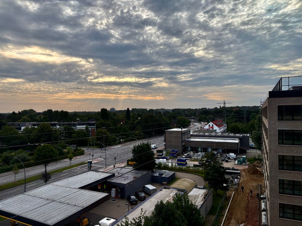 Blick von meiner Baustelle Richtung Stadtpark. Davor eine Tankstelle und Straße. Das Gebäude der Zeugen Jehovas, in dem der Anschlag auf sie stattfand. Der Himmel bewölkt. 