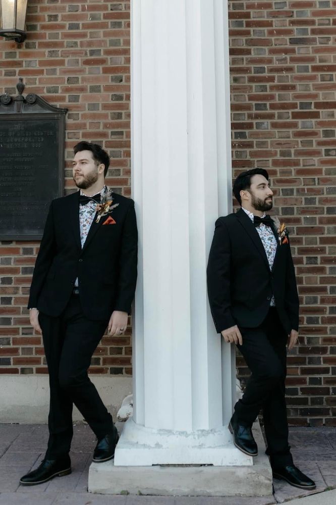 Two men leaning against a white column