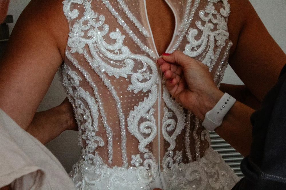 Der Braut wird das Kleid zugemacht