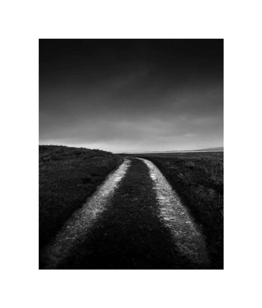Black and white image of a track across a farmers field