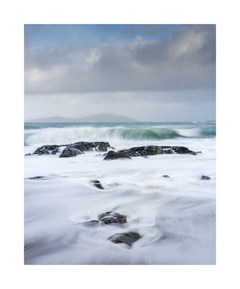 Waves crashing against rocks. Showing movement with a small island in the background 