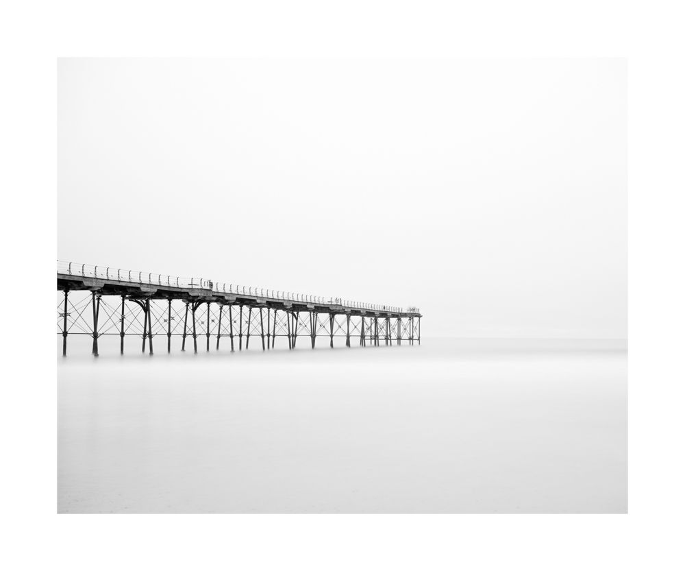 A black and white minimalist image of Saltburn pier. The pier appears from the lift into the milky waters of the North Sea 🌊 