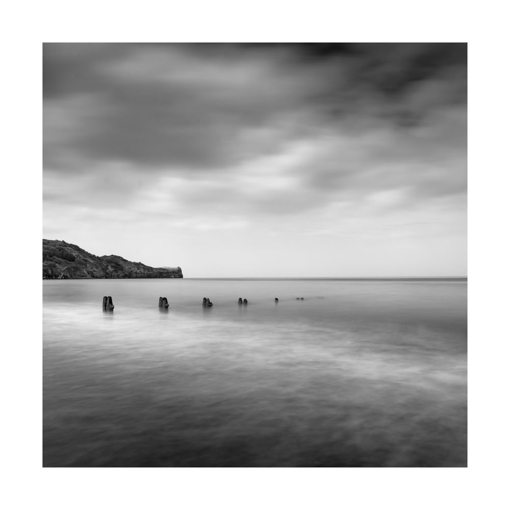 Black and white image of groynes and land gutting out into the North Sea at Sandsend 