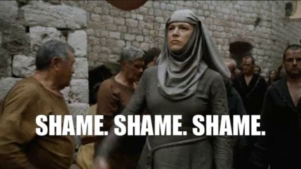 a woman in a hijab is standing in front of a crowd of people and says shame shame shame shame .