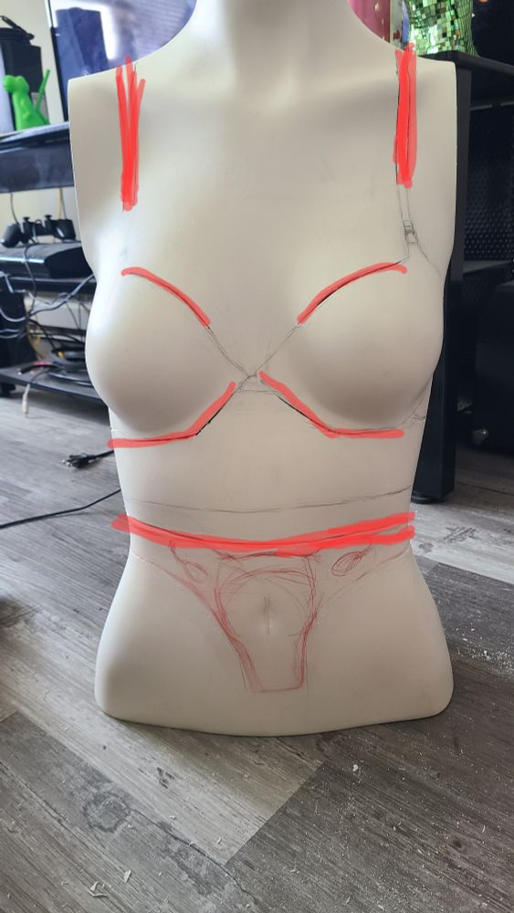A mannequin torsos with red lines indicating areas cut already
