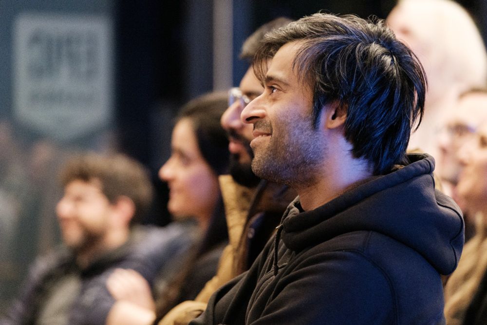 A close up of a person smiling while looking off screen towards the stage