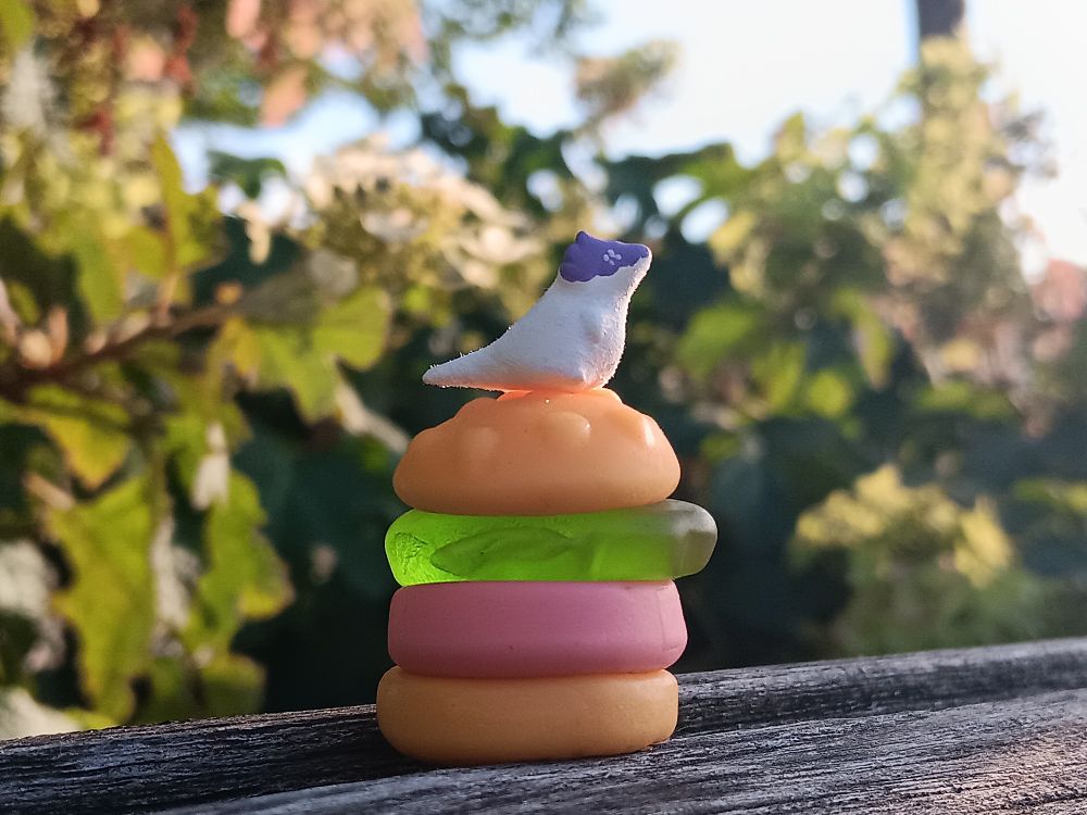 Photo of a tiny mr dinosir miniature sitting on a gummy burger