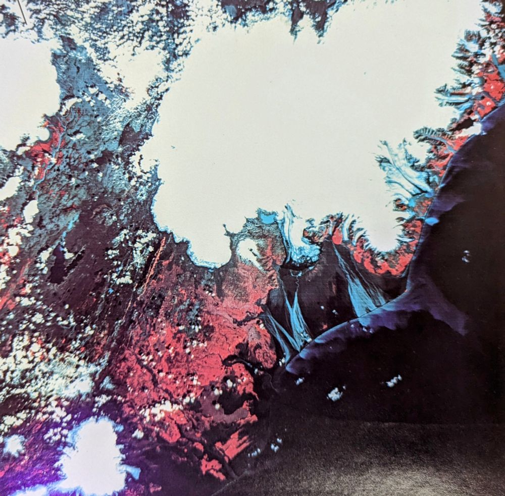 A Landsat false color image showing a big white ice patch and red landforms. 