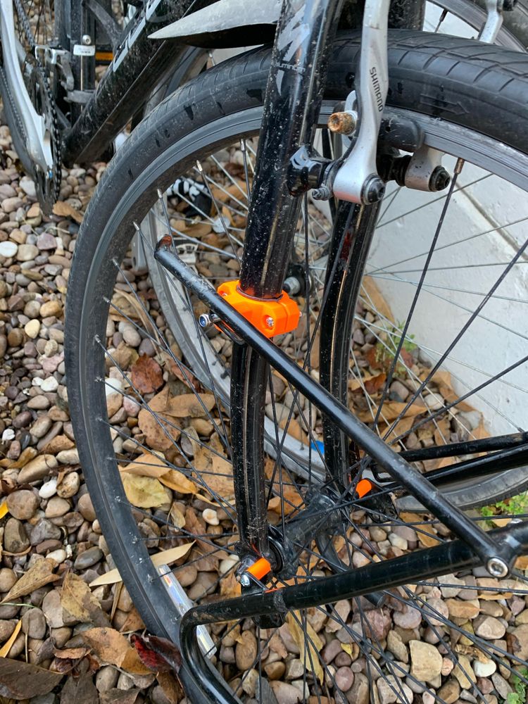 Orange plastic rack mounts in place on a bicycle