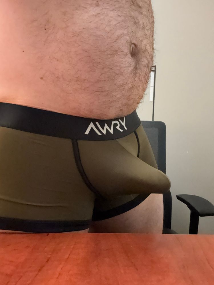 Picture of army green boxer trunks by brand Awry. With an erect penis stretching to be released. 
