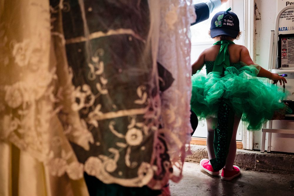 The back of a three-year-old, wearing an enormous green tutu, a green sparkly tail, and a backwards baseball cap that reads T-Red is best!