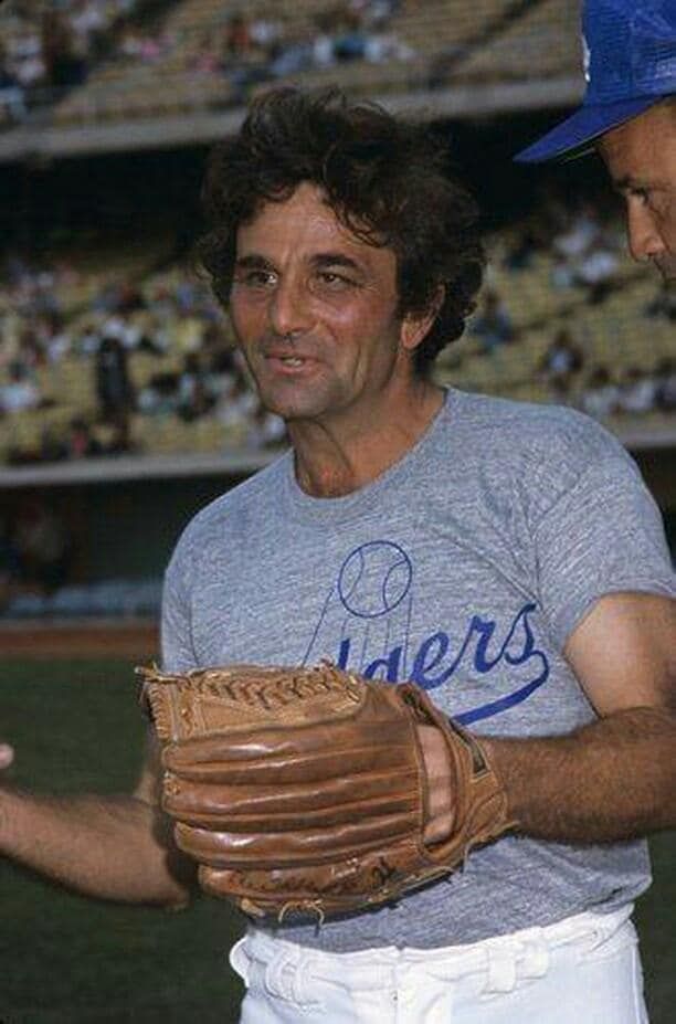Peter Falk wearing a heather grey t-shirt with a blue Dodgers logo holding a baseball mitt