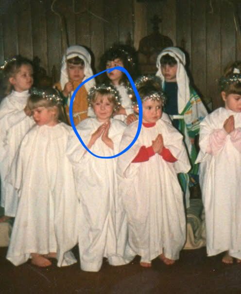 Children’s nativity from the 80s. Children at front wearing white sheets with silver tinsel in their hair. Children at the back are shepherds with tea towels on their heads.