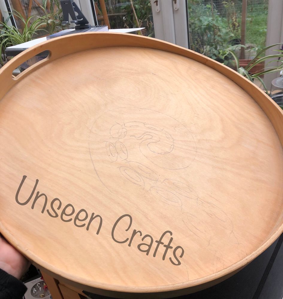 Circular wooden tray with light pencil sketch of an octopus tentacle.