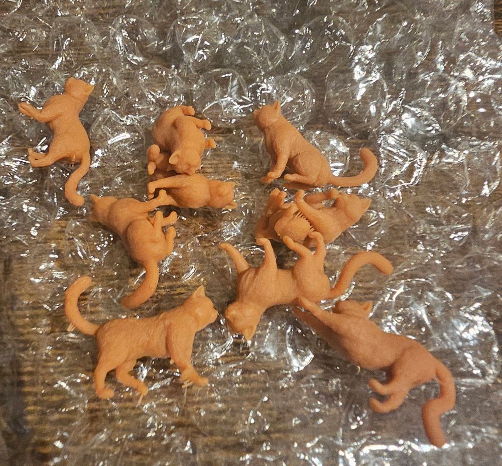 9 clearly 3d printed cat miniatures, unprimed and unpainted.