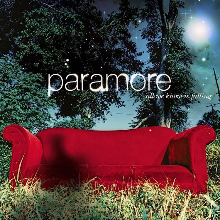 Paramore’s album all we know is falling. Red couch resting in over grown weeds, surrounded by trees 