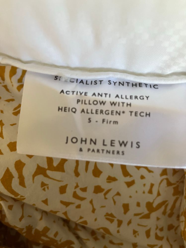 A tag on a pillow describing it as synthetic and firm  and anti allergy. 