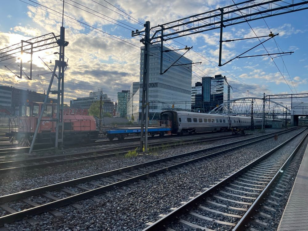 An SJ X2000 train being pulled by a much smaller locomotive