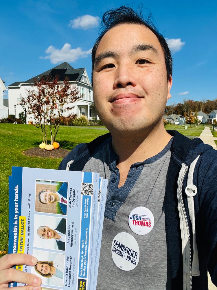 Picture of Jon canvassing an exurban community holding pieces of Democratic slate literature which standing in front of a maple tree turning red with pumpkins on the ground underneath the tree