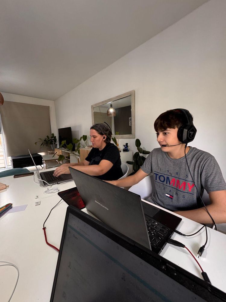 Yanina and Juan Cruz sit side by side, working on two different computers. 