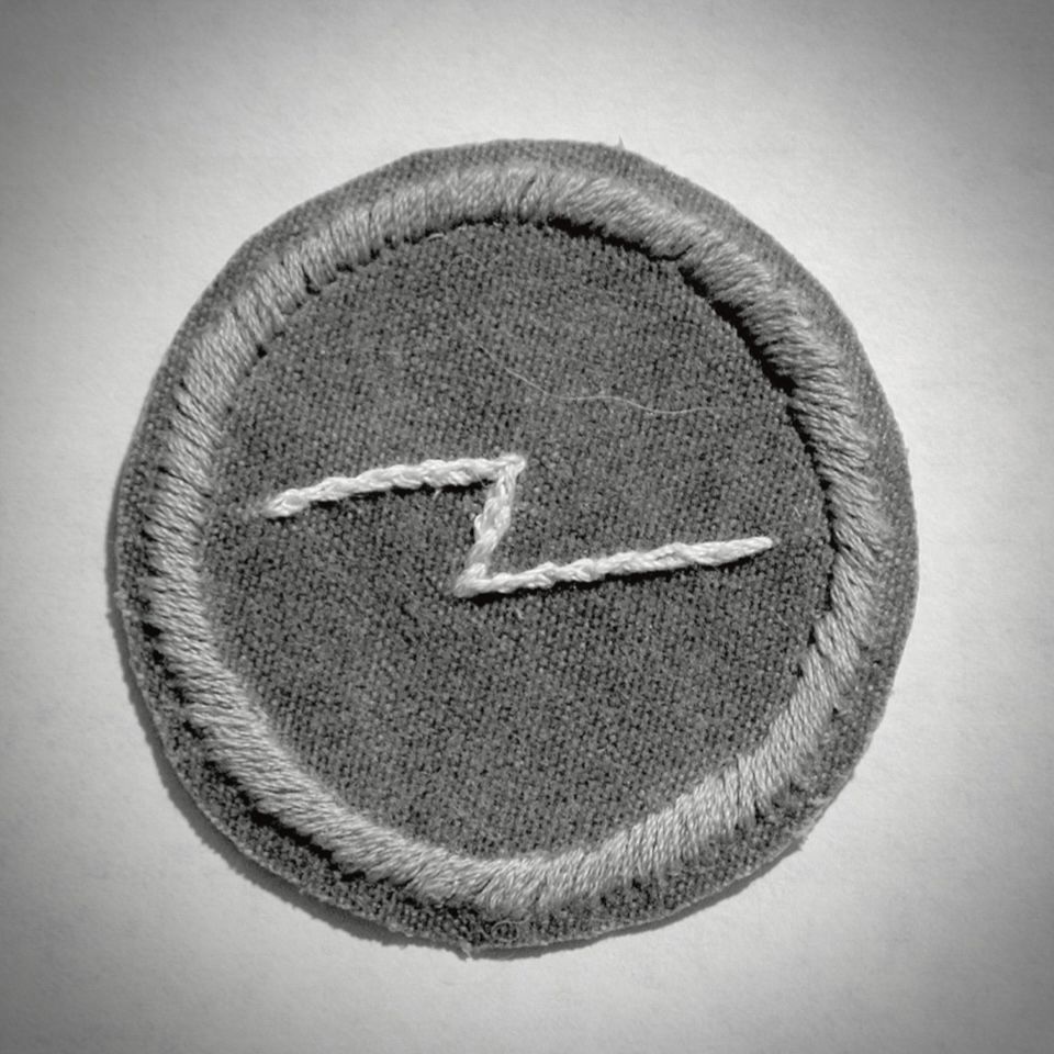 Embroidered patch with circular border and lightning bolt.