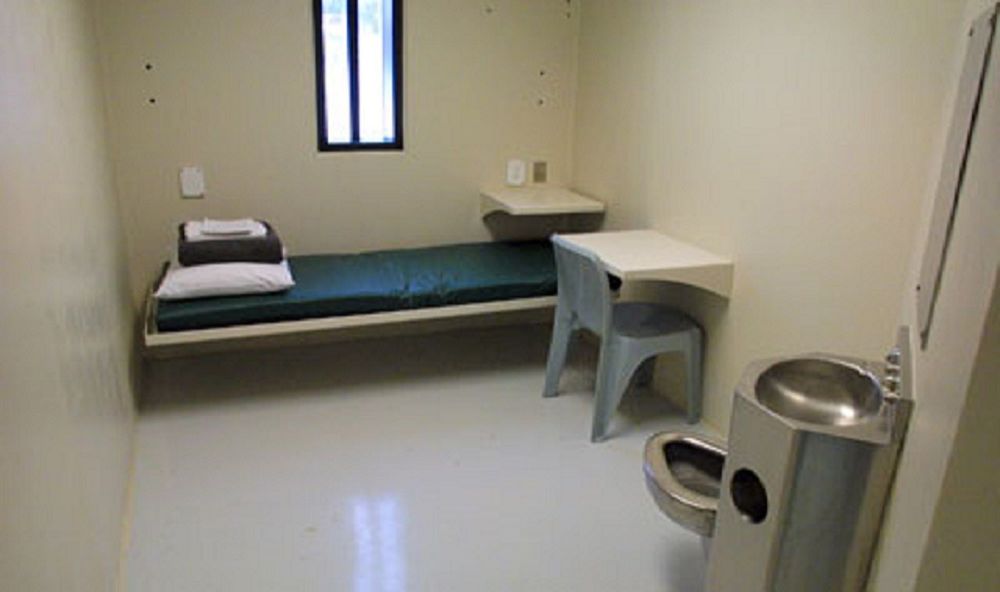 Interior of a prison cell, featuring a stainless steel sink/toilet combo unit.