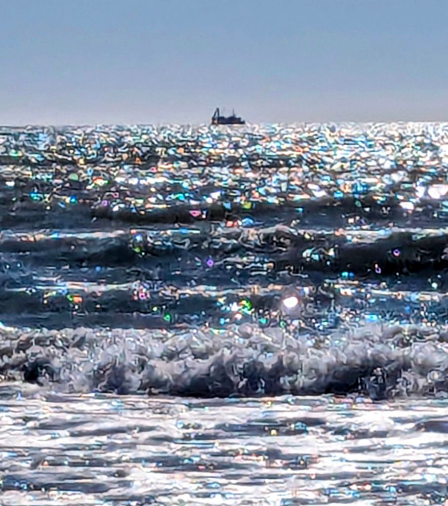 A shot of a ship in the ocean off the coast of the South Island, New Zealand. Unusual fractal patterns and colours on the waters surface.