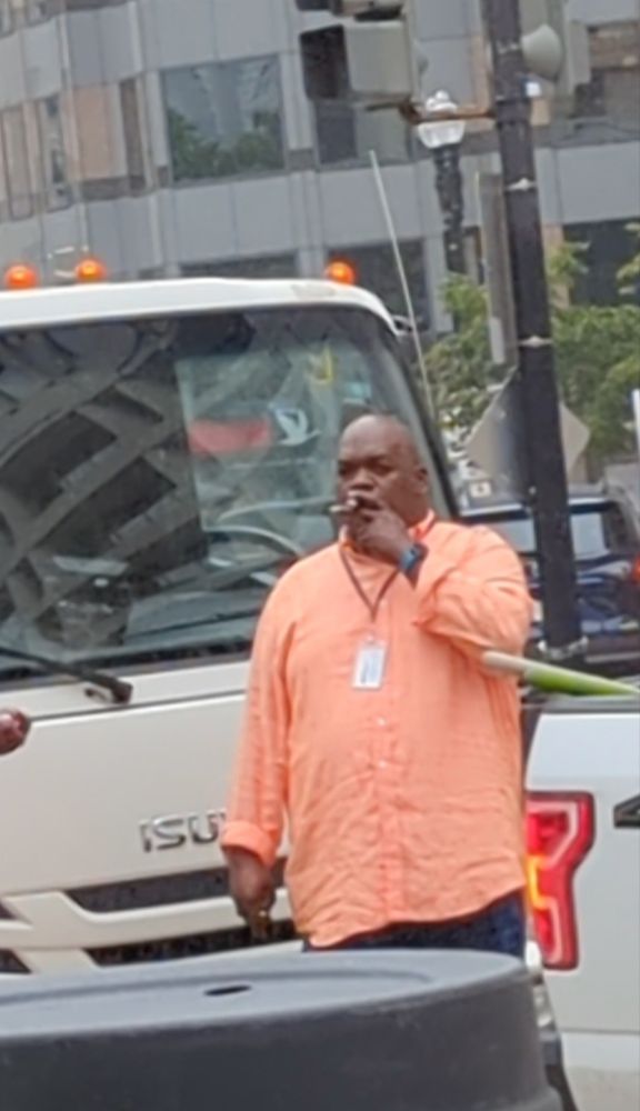 Mr. Smith smoking a cigar in front of a trash truck at the sweep of the DC Downtown Day Services Center.